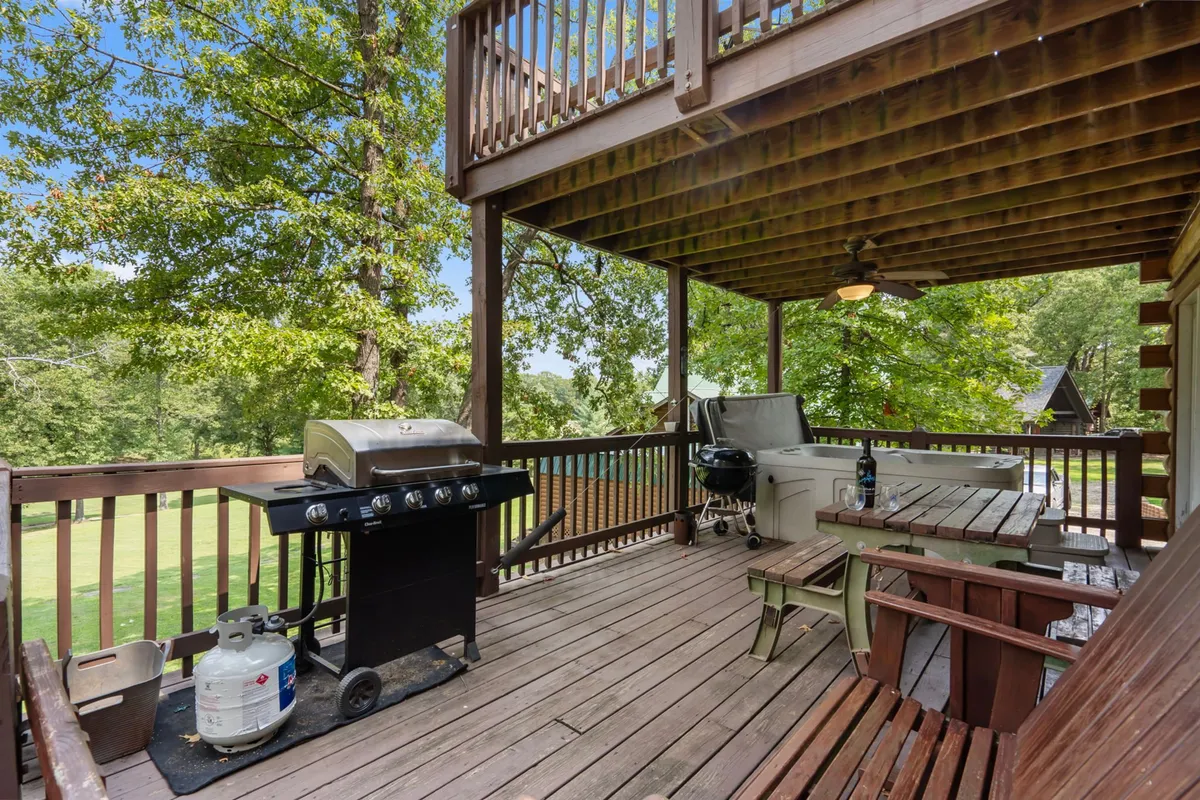 An inviting deck scene featuring a modern grill, a bubbling hot tub, outdoor seating, and lush greenery all around. The image conveys comfort and the opportunity to unwind after outdoor adventures, with space for alfresco dining or a soothing soak.