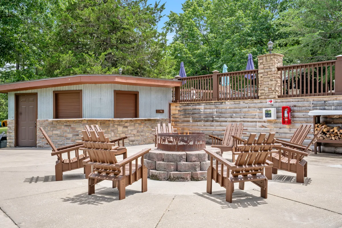 A cozy fire pit area surrounded by wooden chairs and lush greenery, inviting guests to gather, tell stories, and enjoy the warmth of the fire under the open sky.