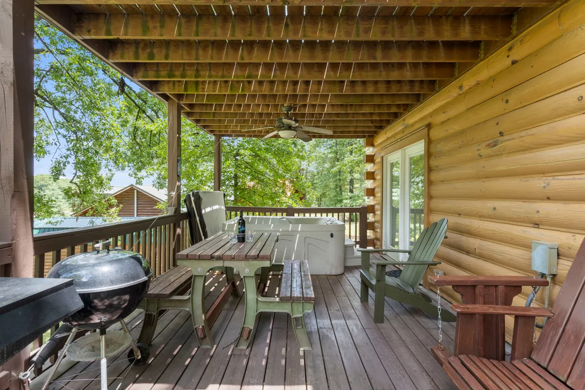 A wooden deck featuring a private hot tub, comfortable outdoor seating, and a grill, all surrounded by lush trees. The space exudes relaxation and intimacy, perfect for unwinding with a partner while enjoying nature and starry evenings.